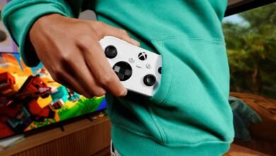 يد تحكم Xbox Nano البيضاء في جيب لاعب أمام شاشة ألعاب