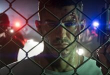 جيسون خلف سياج في لقطة رسمية من GTA 6 مع أضواء الشرطة في الخلفية
